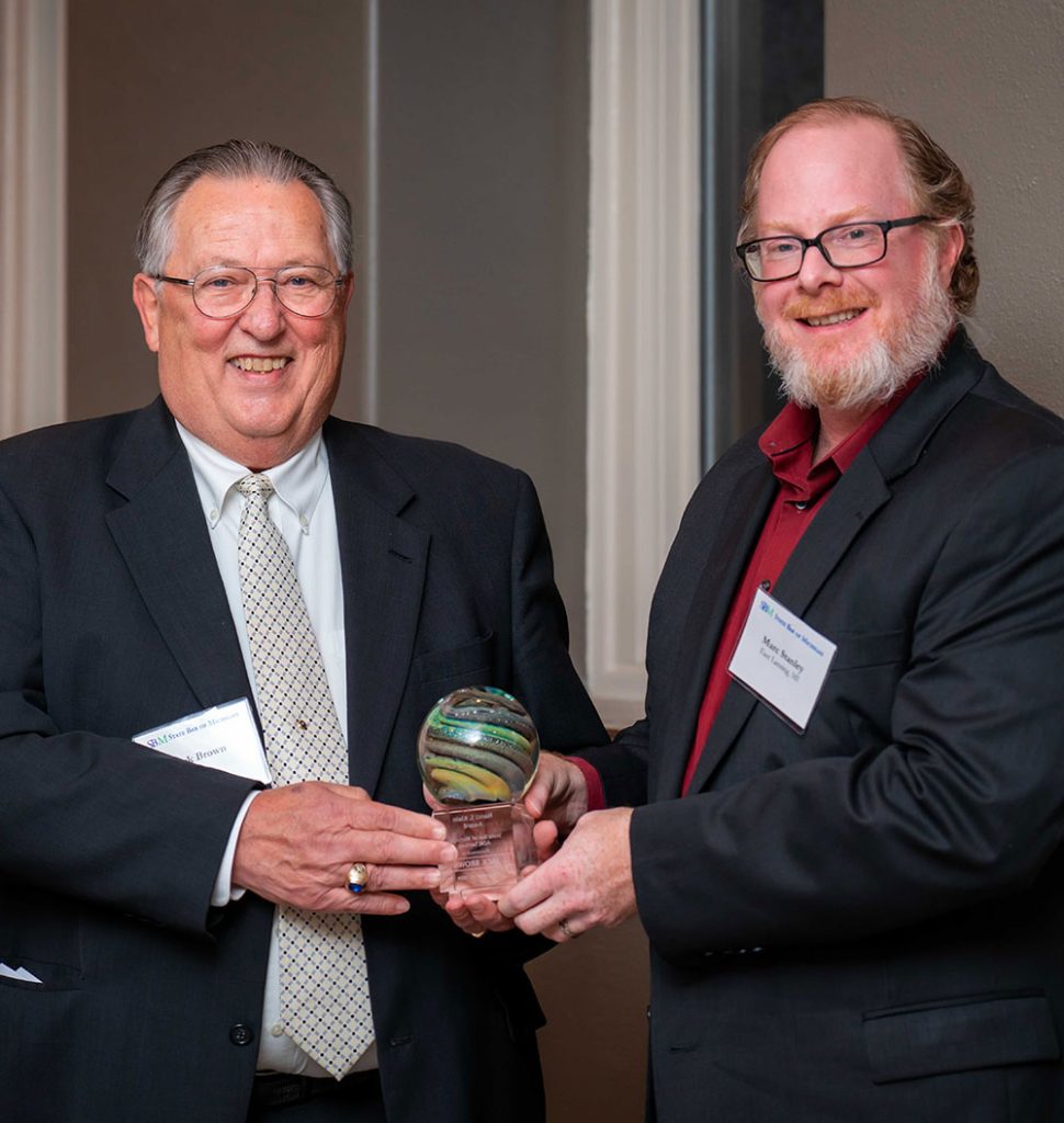 Jack Brown receives a round award from Marc Stanley